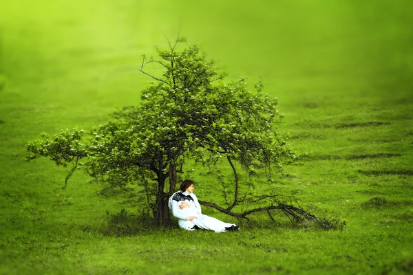 Mujer embarazada sentada sola bajo un hermoso árbol en el sumidero — Foto de Stock