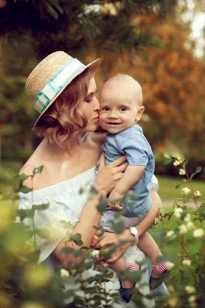 Piękna młoda matka w letni kapelusz całuje dziecko w lato o Obraz Stockowy