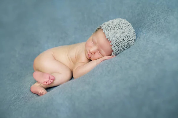 Pasgeboren babyjongen slapen in de foetushouding op een blauwe backgr — Stockfoto