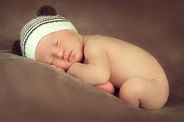 Nouveau-né garçon dormir paisiblement dans la position foetale sur un Images De Stock Libres De Droits