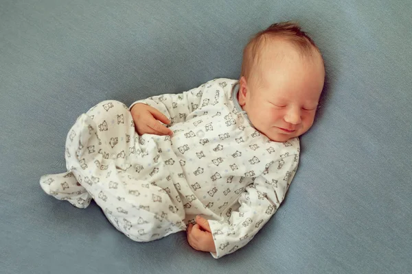 Nouveau-né garçon endormi sur un fond bleu en pyjama blanc wi Image En Vente