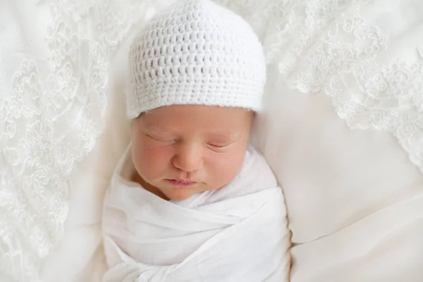 Новорожденный 7 дней, завернутый в белую пеленку и шапку и спит — стоковое фото