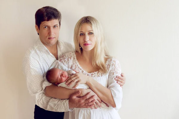 Hermosa pareja en ropa blanca posando con un bebé recién nacido en —  Fotos de Stock