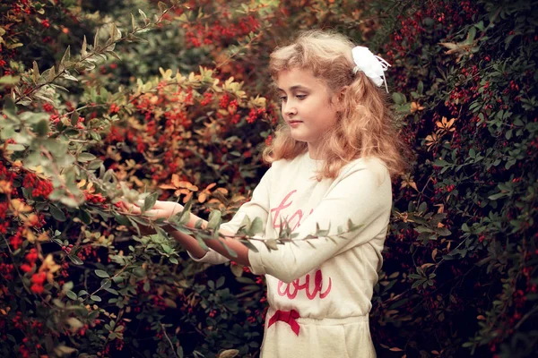 Linda menina loira no verão cuida do arbusto barberry — Fotografia de Stock