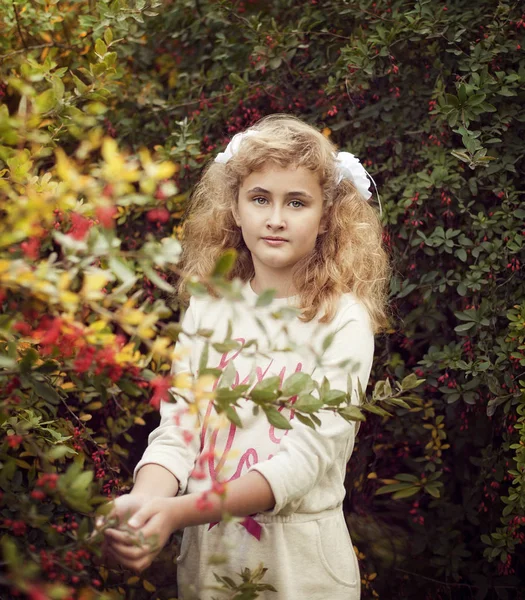 Schönes blondes Mädchen im Sommer kümmert sich um Berberitzenbusch — Stockfoto