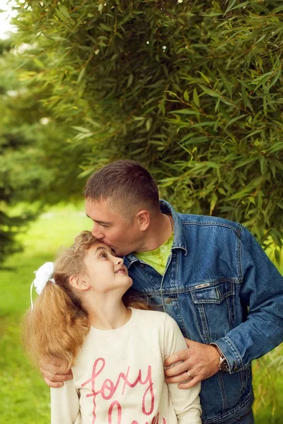 Отец обнимает дочь подростка летом на открытом воздухе, счастливая семья отдыхает — стоковое фото