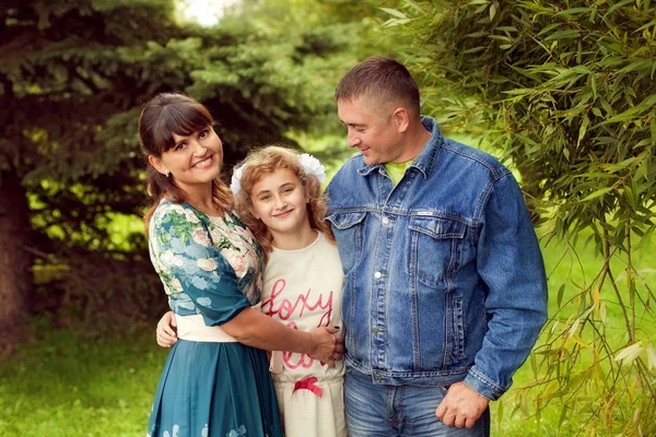 Нормальная счастливая семья, позирующая в парке маме, папе и дочери 1 — стоковое фото