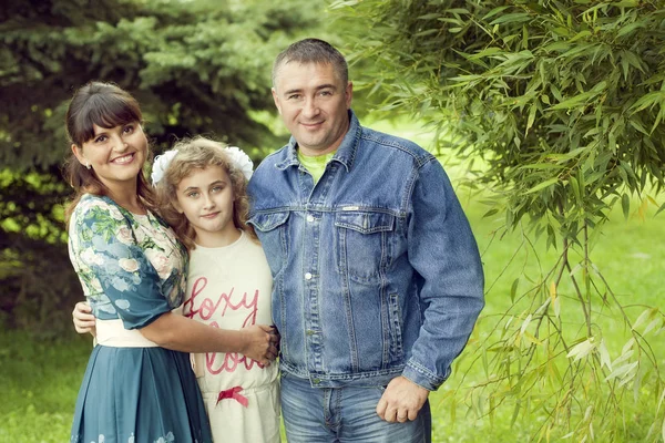 Una familia feliz normal posando en el parque mamá, papá y su hija 1 —  Fotos de Stock