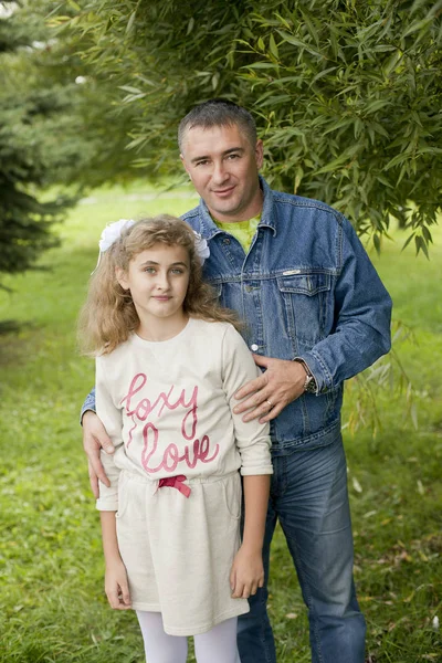 Отец обнимает дочь подростка летом на открытом воздухе, счастливая семья отдыхает — стоковое фото