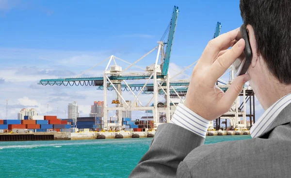 Businessman use smart phone for logistic business, in the background container terminal with cranes