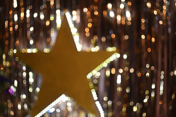 Christmas gold background. Golden holiday glowing background. Defocused background with luminous star.