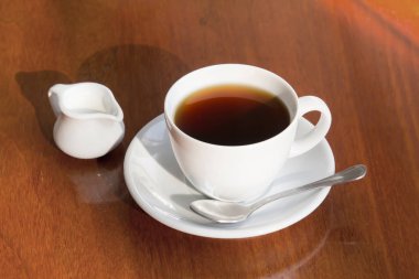 Bir fincan sade kahve ve süt ahşap tablo.