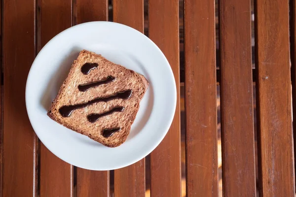 在木桌上的白色磁盘在烤面包上巧克力酱 — 图库照片