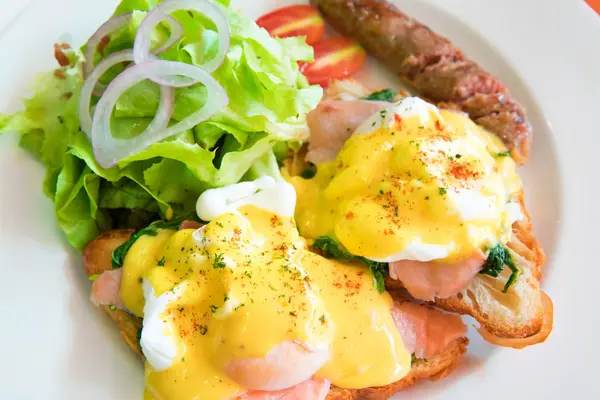 Egg benedict with smoked salmon, sauce, and grill hot dog — Stock Photo, Image