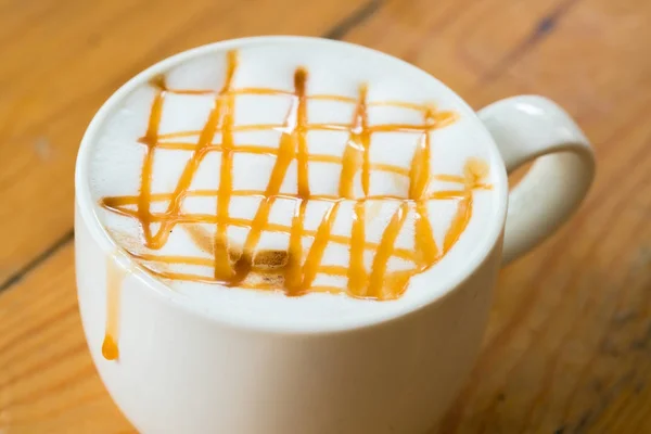 Sıcak macchiato kahve karamel ahşap masa üzerinde beyaz Kupası ile — Stok fotoğraf