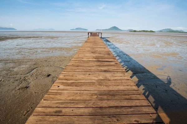 Puente de madera sobre tierra se extiende en el mar durante el tiempo de marea baja — Foto de Stock