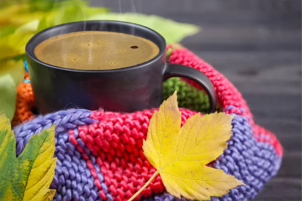 Sort kaffe i et sort krus indpakket i et varmt, farvet, strikket - Stock-foto