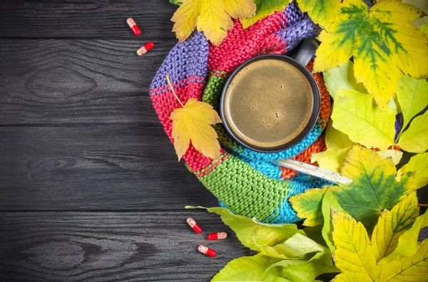 Autumn still life: A cup of hot coffee and a thermometer wrapped — Stock Photo, Image