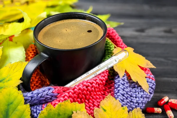 Efterårsstilleben: En kop varm kaffe og et termometer indpakket - Stock-foto