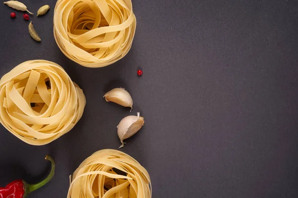 Pasta Top view. Two Fettuccine nests on a gray background with s — Stock Photo, Image