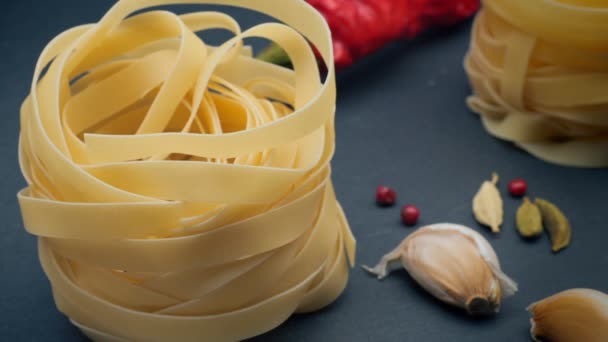 4K video. Pasta: fettuccine nesten op een grijze achtergrond met specerijen: hete peper, venkelzaad en chilipepers. Dimmen en bliksem. B-Roll, element voor videoproject . — Stockvideo