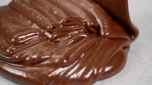 Putting chocolate dough on a baking sheet covered with parchment for baking cake — Stock Video