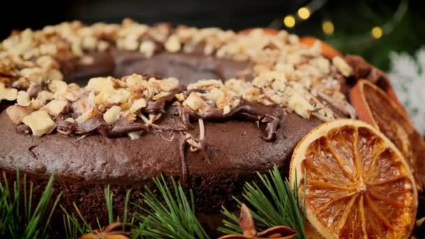 Ünnepi karácsonyi sütemény narancs szeletekkel és dióval az újévi koszorú hátterén. Körmozgás — Stock videók