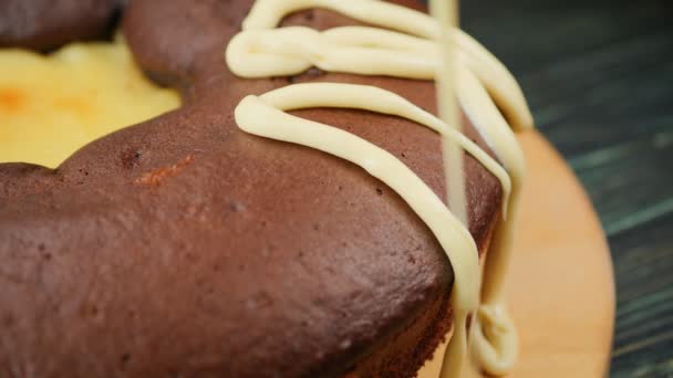 Fazer comida - sobremesa. Decorar o bolo com chocolate branco e preto, polvilhando com nozes esmagadas. Close-up. 4k vídeo . — Vídeo de Stock