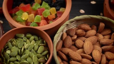 Sağlıklı kahvaltı. Granola. Yulaf ezmesi, arpa gevreği. Fındık: Fındık, badem, kaju. Kuru üzümler, hurmalar, kuru üzümler. Siyah, ahşap arka plandaki kil kaselerde. 4k video