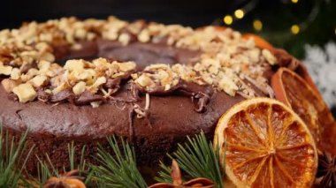 Yılbaşı çelenklerinin arka planında portakal dilimleri ve fındıklı Noel keki. Çember hareketi