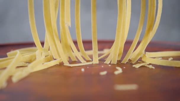 Vařím domácí nudle. Fettuccine po řezání padá na hliněnou destičku. Zpomalený pohyb — Stock video