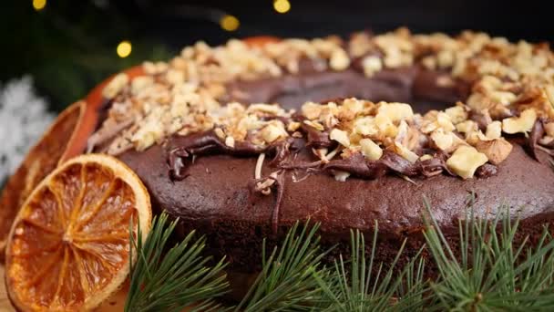 Pastel de Navidad festivo con rodajas de naranja y nueces en el fondo de una guirnalda de Año Nuevo. Movimiento circular — Vídeo de stock