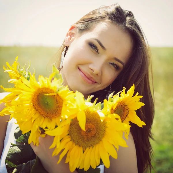 Mujer joven sosteniendo girasoles — Foto de Stock