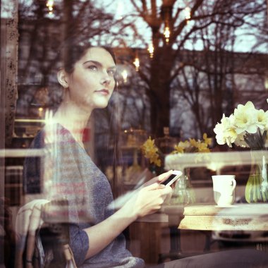 Kafede akıllı telefon kullanan bir kadın.