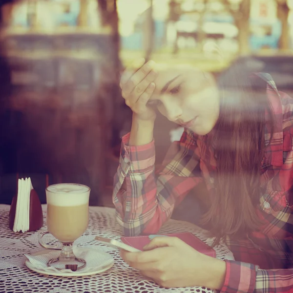 Kobieta za pomocą smartfona w kawiarni — Zdjęcie stockowe