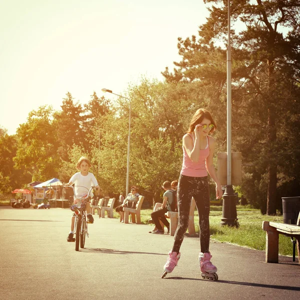 Meisje op rolschaatsen en jongen op fiets — Stockfoto