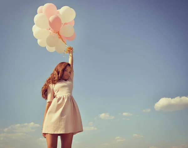 Vrouw met ballonnen in de blauwe hemel — Stockfoto