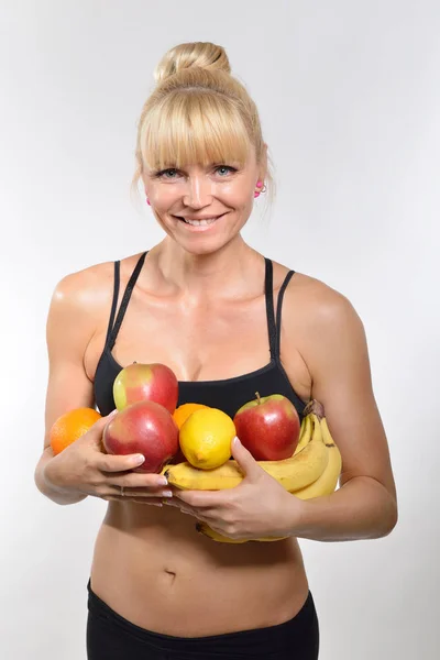 Mulher atlética segurando frutas — Fotografia de Stock