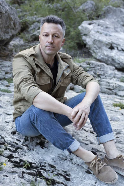 Hombre de moda sentado en rocas — Foto de Stock