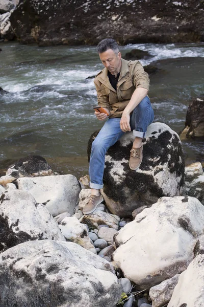 Uomo attraente seduto sulle rocce — Foto Stock