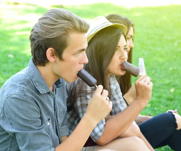 Hombre joven y mujeres comiendo helado de chocolate al aire libre en verano —  Fotos de Stock