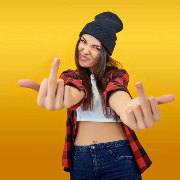 Hipster chica en jeans, camisa a cuadros y sombrero mostrando el medio f —  Fotos de Stock