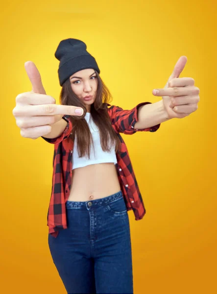 Хипстерская девушка в джинсах, проверенная рубашка и шляпа, показывающая средний финг — стоковое фото