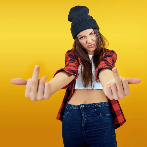 Hipster menina em jeans, camisa verificada e chapéu mostrando meio fing — Fotografia de Stock