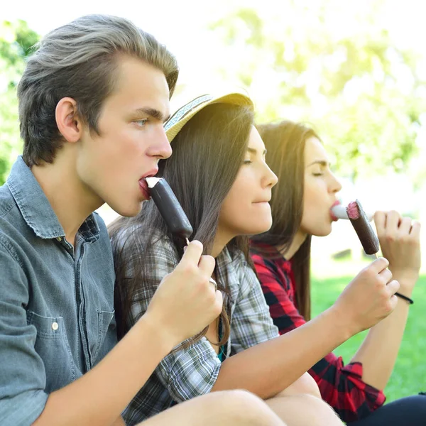 Hombre joven y mujeres comiendo helado de chocolate al aire libre en verano —  Fotos de Stock