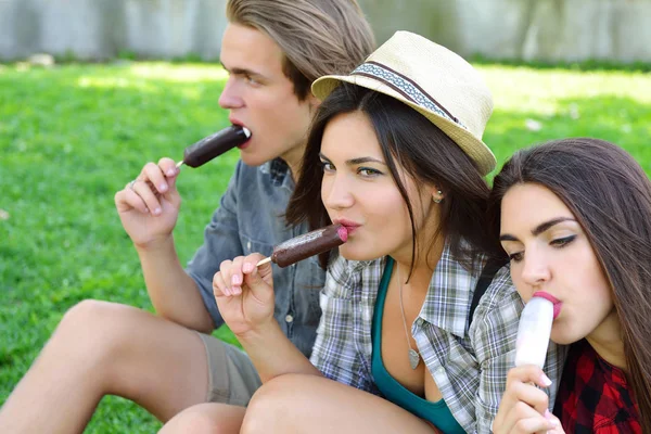 Hombre joven y mujeres comiendo helado de chocolate al aire libre en verano —  Fotos de Stock