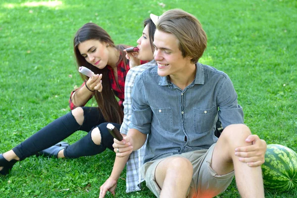 Hombre joven y mujeres comiendo helado de chocolate al aire libre en verano —  Fotos de Stock