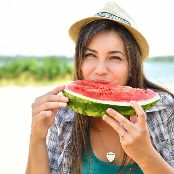 Счастливая молодая женщина ест арбуз на пляже. Стиль жизни молодежи — стоковое фото
