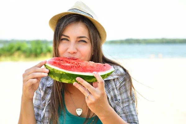 Счастливая молодая женщина ест арбуз на пляже. Стиль жизни молодежи — стоковое фото