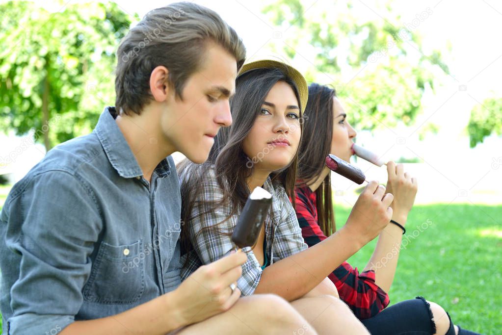 Young man and women eating chocolate ice-cream outdoor in summer
